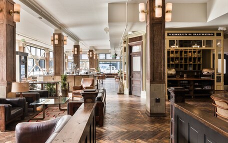 A spacious lobby with a wooden floor, leather seating, and a Verblun S. Hafberg wine cellar.
