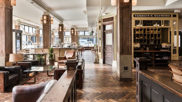 A spacious lobby with a wooden floor, leather seating, and a Verblun S. Hafberg wine cellar.