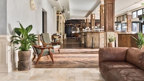 A spacious lobby with a herringbone floor, wooden furniture, and a bar area in the background.