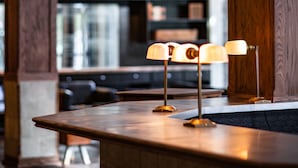 A wooden reception desk with three lamps, a bookshelf in the background, and a modern interior design.