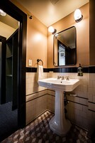 Un baño con un lavabo blanco, un espejo y una toalla colgada en un perchero.