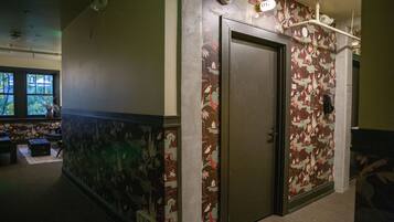 A hallway with a door, patterned wallpaper, and a window with a view of trees.