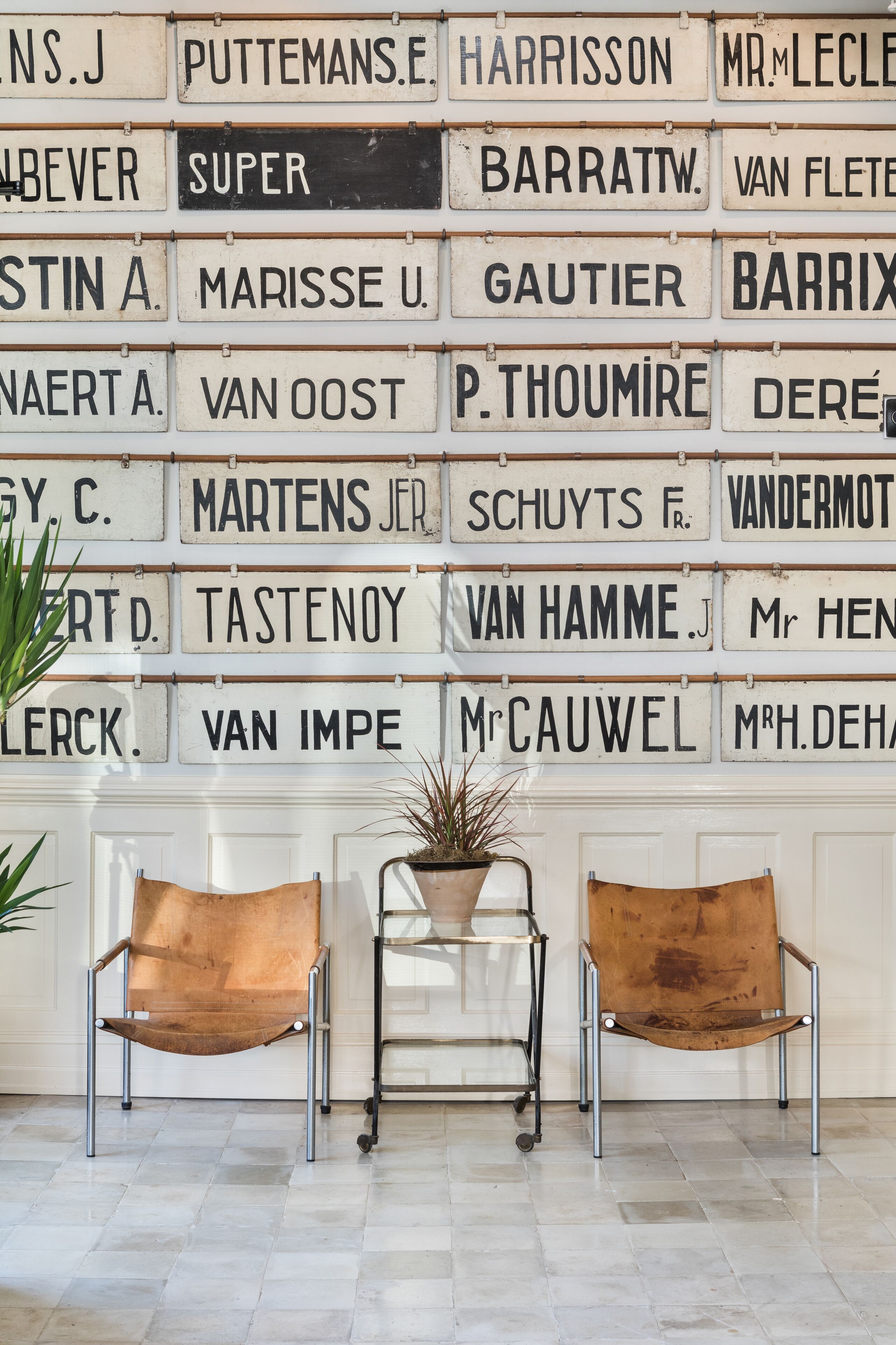 A wall with nameplates and two leather chairs in a room.