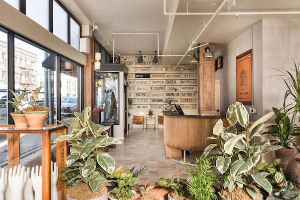 A modern interior with a reception desk, potted plants, and a wall with names.