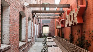 An outdoor dining area with brick walls, wooden tables, and benches.