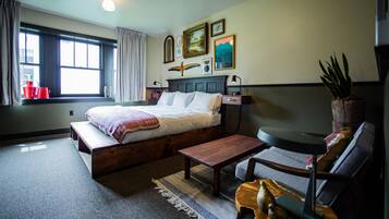 A bedroom with a bed, bedside table, chair, and a window with curtains.