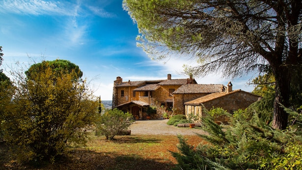 A stone house with a tiled roof, surrounded by dense greenery and a clear sky. - Le Roghete (Acquapendente)
