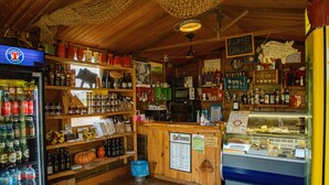 A rustic bar with wooden shelves stocked with bottles, a refrigerator, and a display case. - Le Roghete (Acquapendente)
