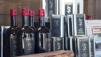 Bottiglie di olio d'oliva Le Roghete e scatole dello stesso prodotto su un piano di legno.