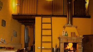A cozy room with a fireplace, wooden furniture, and a hanging light fixture. - Le Roghete (Acquapendente)