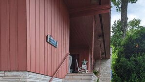 Eine Treppe führt zu einer Veranda mit einer Steinmauer und einer roten Gebäudefassade.