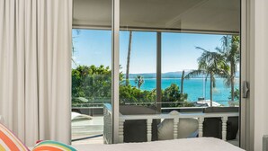 Une chambre avec une grande fenêtre donnant sur une piscine et l’océan.
