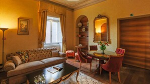 Une pièce comprenant un canapé, une table à manger avec des chaises, un miroir et une cheminée.