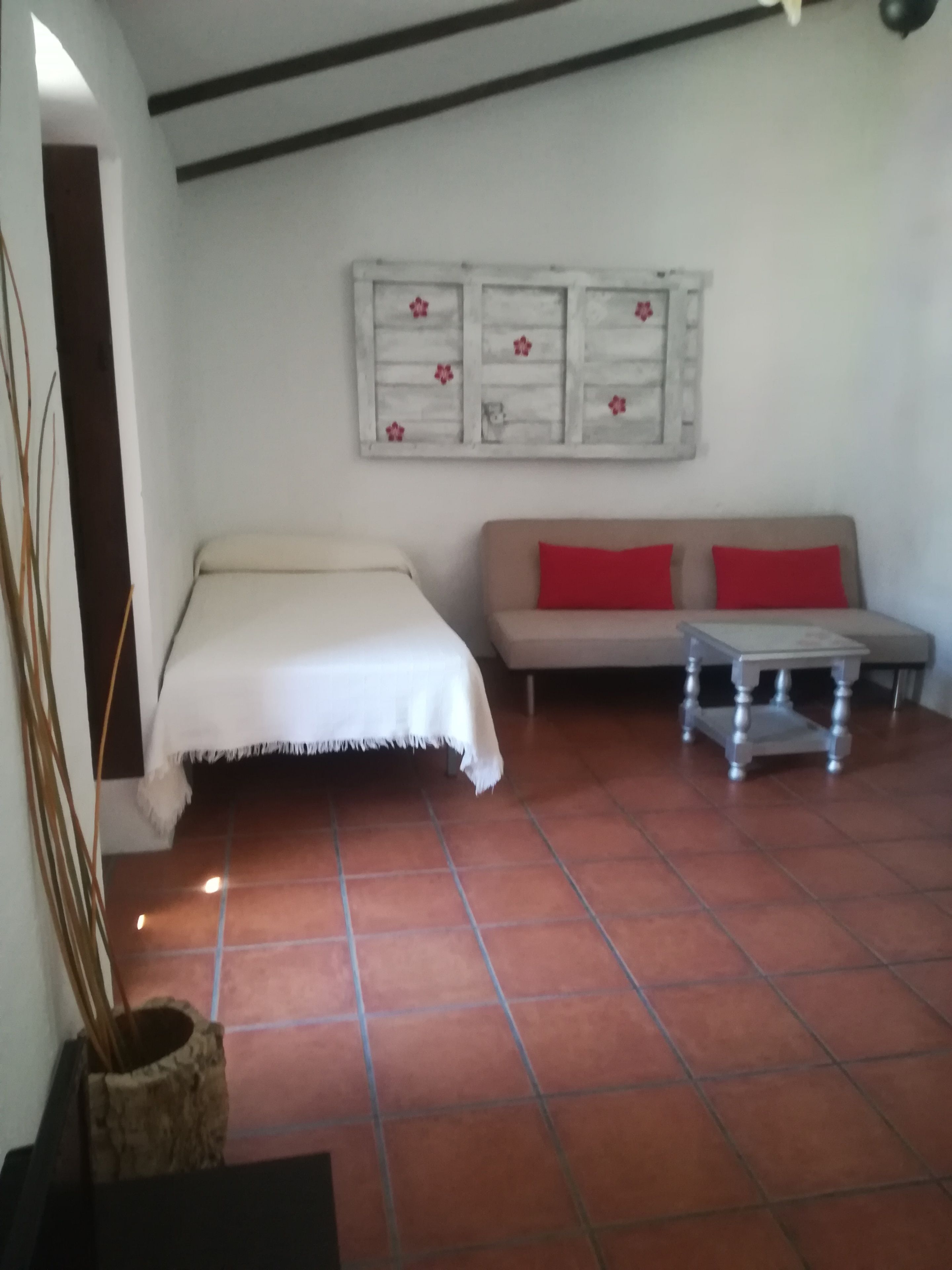 Una habitación con cama, sofá, una mesita y un adorno en la pared.
