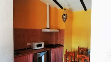 Cocina compacta con microondas, refrigerador y sillas de madera.