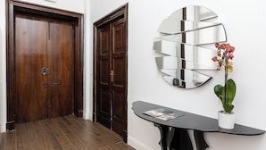 A wooden door, a wall-mounted mirror, and a table with a potted plant. - Prestigious Apartments Via Barberini (Rome)
