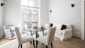 A modern living room with a glass dining table, white sofas, and a plaid armchair. - Prestigious Apartments Via Barberini (Rome)