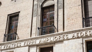 A building facade with the inscription "FERRI AMPLIORS AIDES" and a balcony with a metal railing. - Prestigious Apartments Via Barberini (Rome)