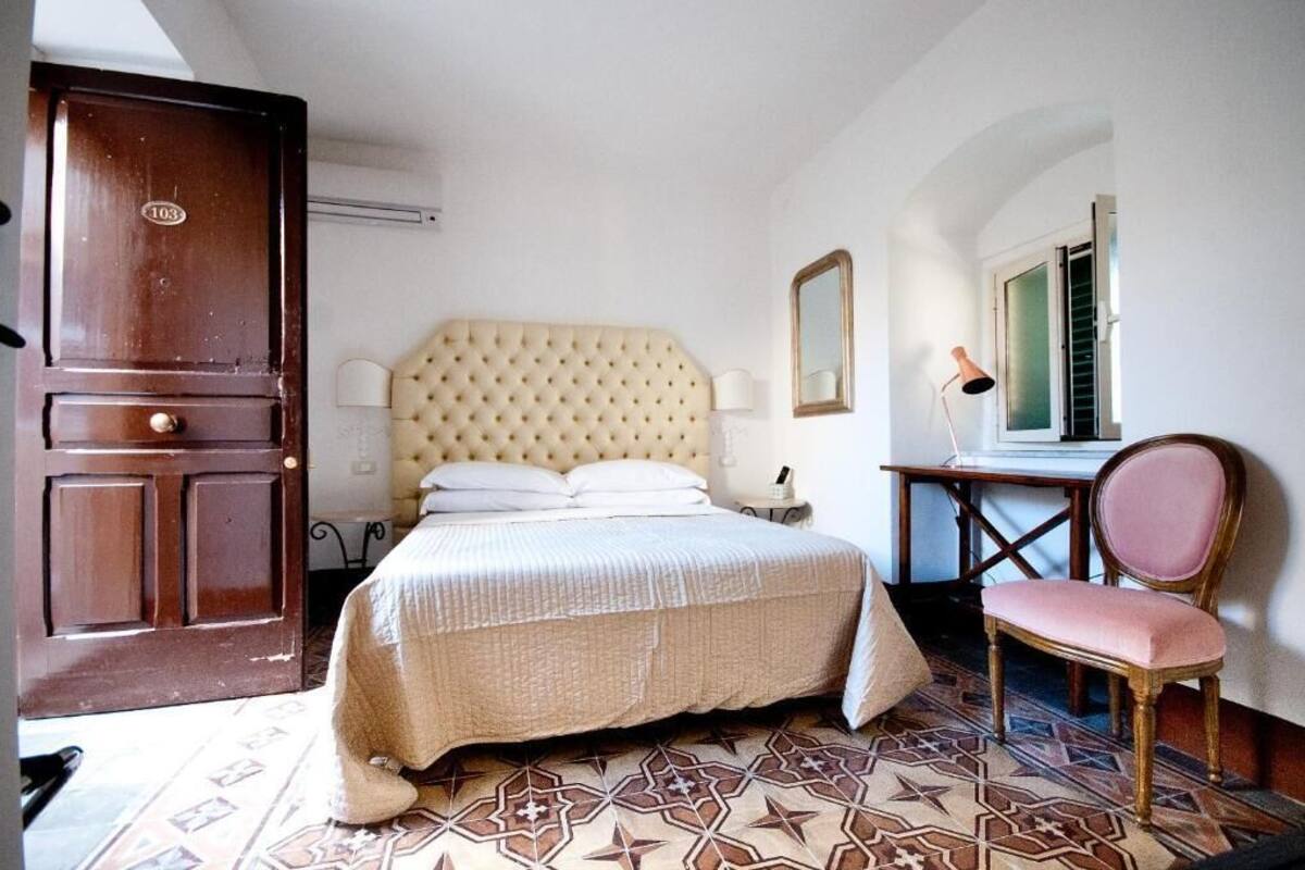 Un dormitorio con una cama grande, una puerta de madera, una silla y una mesita.