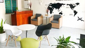A modern lounge area with a world map mural, a wooden reception desk, and several seating options including a round table and chairs. - Mini Hotel (Phnom Penh)