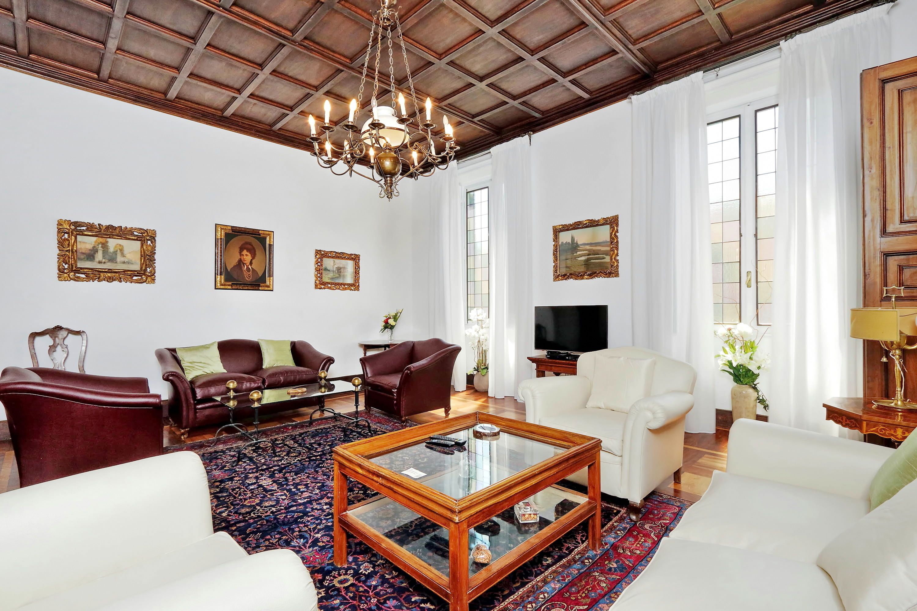 A spacious living room with a large wooden coffee table, two sofas, a red armchair, and a television.