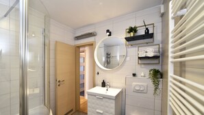 A modern bathroom with a glass shower enclosure, a white vanity with a round mirror, and a towel rack with neatly folded towels. - Apartment First Choice Ilica (Zagreb)
