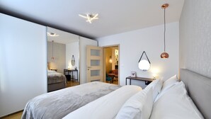 A modern bedroom with two beds, a mirror, a bedside table, and a hanging light fixture. - Apartment First Choice Ilica (Zagreb)