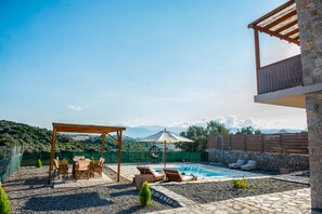Ein Garten mit Schwimmbad, Gartenmöbeln und einer Pergola.