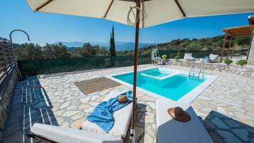 Relax by the pool surrounded by lush greenery and distant hills.