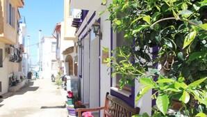 Une rue étroite, bordée de bâtiments des deux côtés, avec un banc et des plantes en pot.