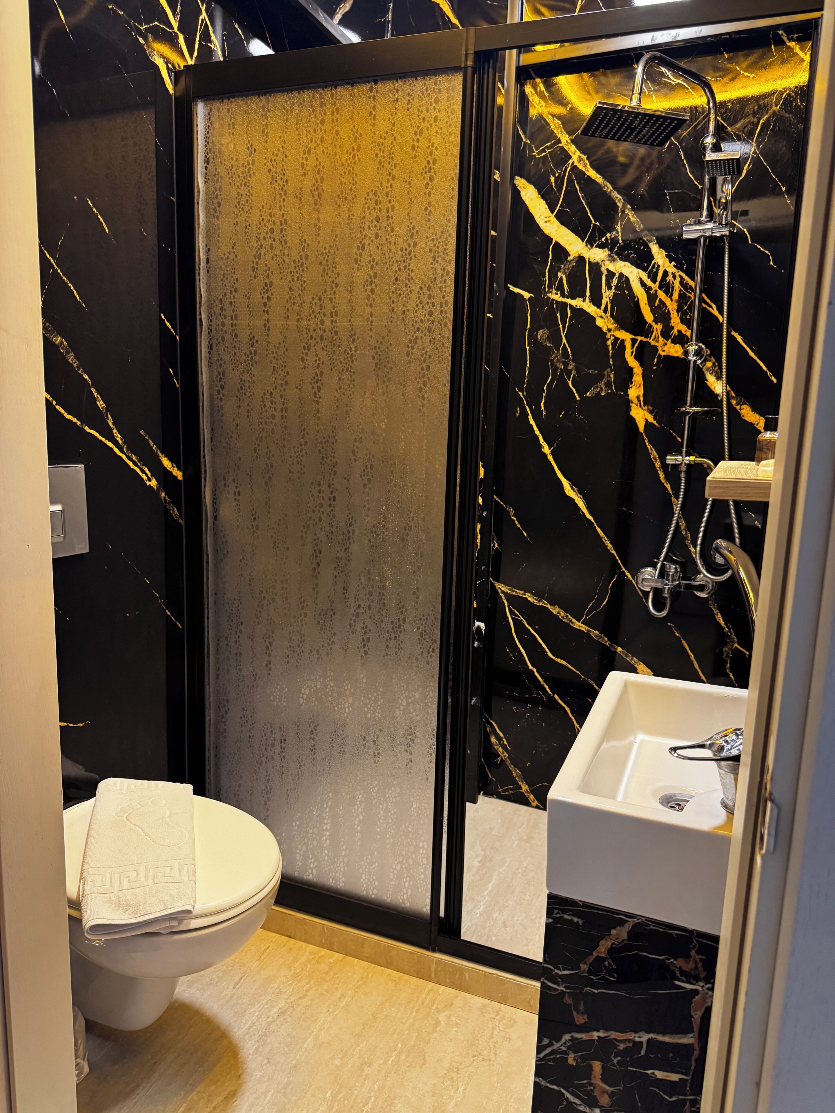 A bathroom with a toilet, a sink, and a shower area with a glass door.