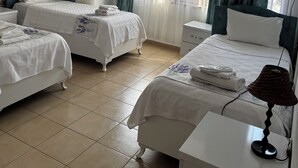 Une chambre d’hôtel avec deux lits, un ventilateur de plafond, une lampe en osier et une fenêtre avec des rideaux.