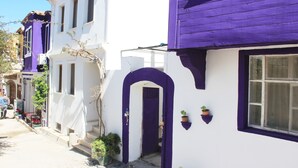 Une rangée de bâtiments blancs agrémentés de touches violettes, notamment au niveau des portes et des encadrements de fenêtres.