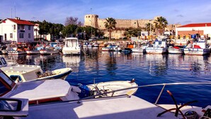 Un port de plaisance avec des bateaux amarrés, un château en arrière-plan et un bâtiment avec un toit rouge.