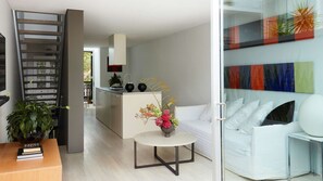 A modern living room with a white sofa, a small round table, and a kitchen area in the background.