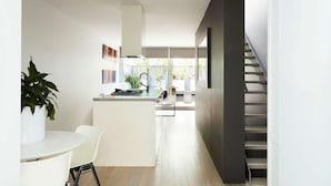 A modern kitchen with a central island, white walls, and a staircase leading to an upper level. - Apartment One by Contemporary Hotels is the quintessential glamorous Darlinghurst apartment for thos (Darlinghurst)
