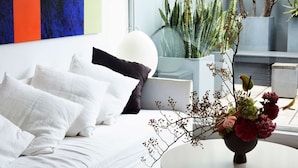 A modern bedroom with a bed, pillows, and a vase with flowers. - Apartment One by Contemporary Hotels is the quintessential glamorous Darlinghurst apartment for thos (Darlinghurst)