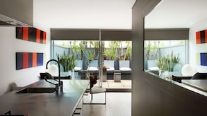A modern interior with a dining area, a seating arrangement, and a view of the outdoor garden. - Apartment One by Contemporary Hotels is the quintessential glamorous Darlinghurst apartment for thos (Darlinghurst)