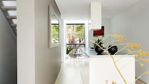 A modern interior with a white staircase, a dining area with a black chair, and a view of trees through a glass door. - Apartment One by Contemporary Hotels is the quintessential glamorous Darlinghurst apartment for thos (Darlinghurst)