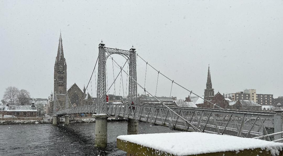 A snow-covered bridge with a gothic-style tower in the background.