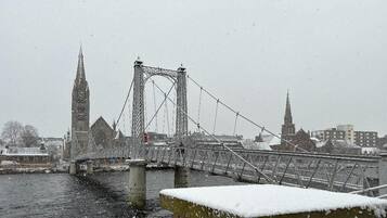 Un puente cubierto de nieve con una torre de estilo gótico al fondo.