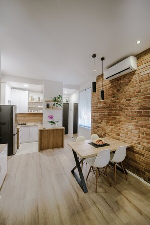 A modern kitchen with white cabinets, a wooden island, and a brick accent wall. - Apartment British Square (Zagreb)