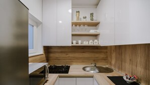 Una cocina moderna con armarios blancos, encimera de madera, pileta de acero inoxidable y un tapete negro.