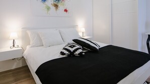 Un dormitorio moderno con una cama grande, paredes blancas y un cuadro abstracto colorido.