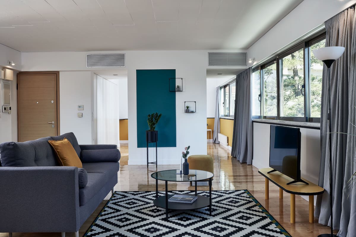 Uma sala de estar moderna com sofá, mesa de centro e vista através de grandes janelas.
