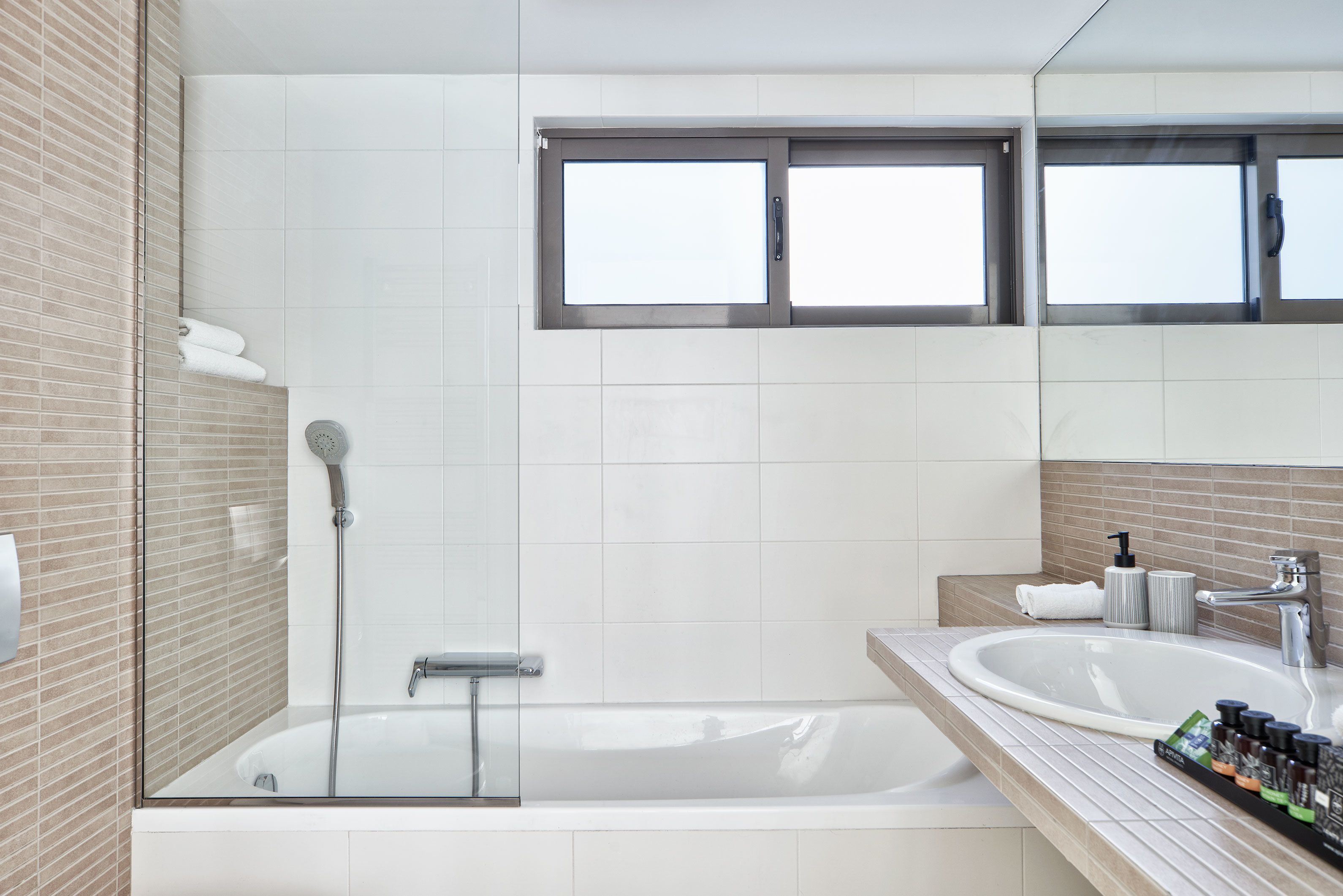 A modern bathroom with a glass-enclosed shower, a large white bathtub, and a vanity with a sink and countertop.