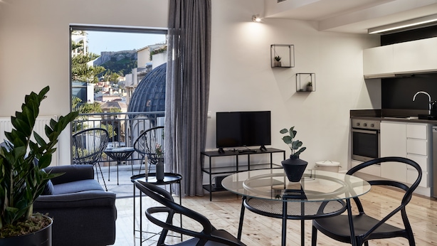 Un apartamento moderno con balcón, comedor, cocina y televisor.