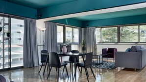 Una sala de estar moderna con comedor, ventanas amplias y un sofá gris.