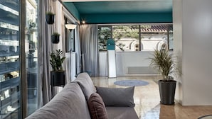 Una sala de estar moderna con sofá, plantas en macetas y vista a un balcón.