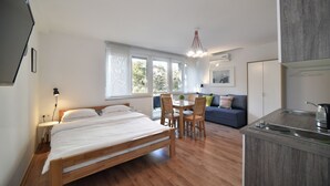 A modern bedroom with a wooden bed, a dining table with chairs, a sofa, and a kitchenette. - Vla Vla Apartments (Zagreb)